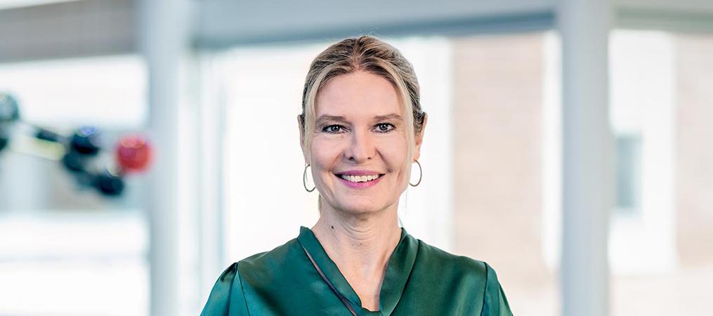 Photo of Regina Fritsche Danielson standing against a railing smiling at the camera